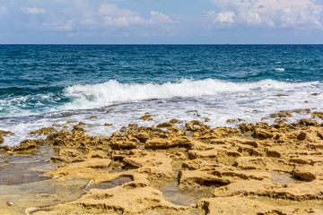 Blue emerald Mediterranean sea water with stone beach in Sliema, Malta. Unearthly rocky Malta shore.