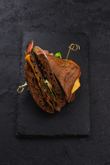 dark ciabatta bread sandwiches with green salads and cream cheeses on black plate