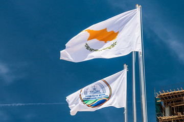 The flag of Agia Napa municipality and the flag of Cyprus. Flags on the flagpole and the stereet lamp post. The wind inflates the flag.
