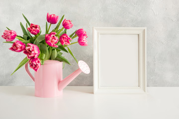 Decorative watering can with pink tulips. Gardening concept.