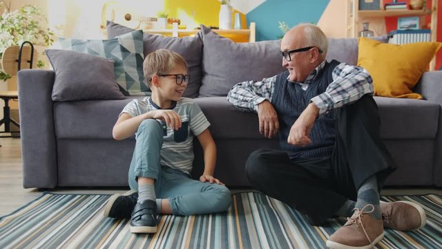 Portrait of grandfather and grandson putting on eyeglasses smiling having fun at home. Happy family, relationship with children and childhood concept.