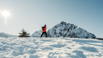  Adventurous man are hiking to the top of a mountain during a vibrant winter sunset. Extreme winter...