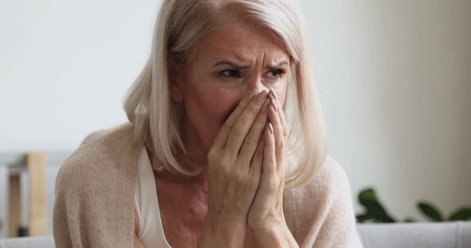 Upset depressed mature old woman crying alone at home