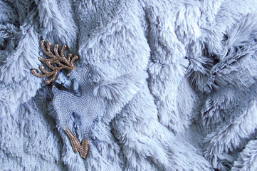 Glass Christmas toy deer with golden horns on a fur plaid.