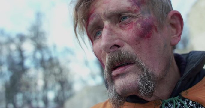Sad chieftain wipes face from blood and looks on killed troops on snow