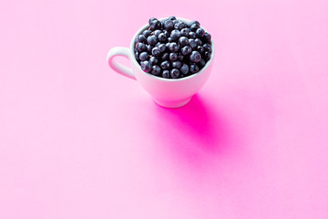 Fresh organic blueberries in ceramic cup . Copy space, isolated on pink background.Fresh raw organic farm blueberry in white cup.harvest. Healthy food. vegetarian food.