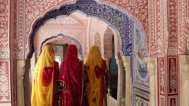 India, Rajasthan, Jaipur, Samode Palace, ladies wearing colourful Saris in ornate passageway - Model released