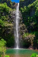 Jungle waterfall cascade in tropical rainforest with rock and turquoise blue pond.