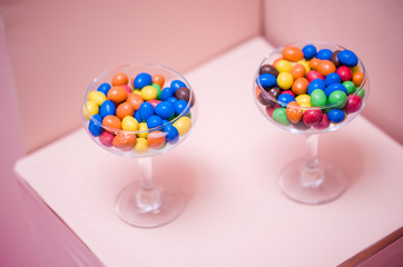 Early-colored round candy in glass glasses. Peanuts in colored chocolate.