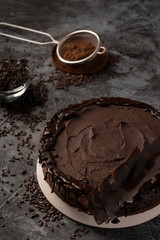 Raw chocolate cheesecake on dark grey background. Healthy organic dessert pie. Cacao and chocolate around