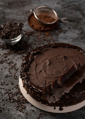 Raw chocolate cheesecake on dark grey background. Healthy organic dessert pie. Cacao and chocolate around