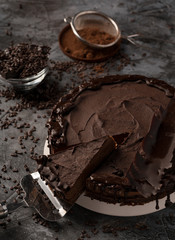 Raw chocolate cheesecake on dark grey background. Healthy organic dessert pie. Cacao and chocolate around