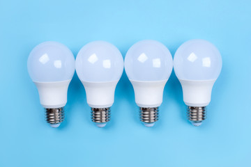 Four LED bulbs on blue background. Saving energy concept. Ftat lay. Top view.