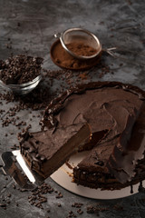 Raw chocolate cheesecake on dark grey background. Healthy organic dessert pie. Cacao and chocolate around