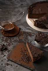 Raw chocolate cheesecake on dark grey background. Healthy organic dessert pie. Cacao and chocolate around