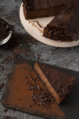 Raw chocolate cheesecake on dark grey background. Healthy organic dessert pie. Cacao and chocolate around