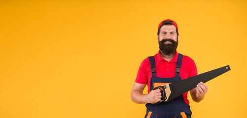 Fototapeta na wymiar Sharp blade of saw. Dangerous job. Feeling manly. Carpenter with saw in hands. Masculinity concept. Handsome man with saw yellow background. Gardener lumberjack equipment. Tools shop copy space