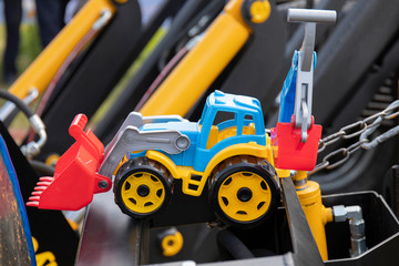 Fototapeta premium Excavator toy standing on a metal construction on a sunny day.