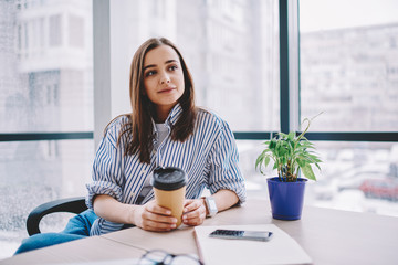 Stylish woman with takeaway beverage in office