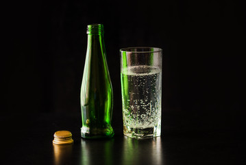 Gassed water in a glass on a black table and black background.