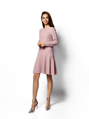 Young beautiful woman posing in new fashion long casual beige color winter dress happy smiling walking on white 