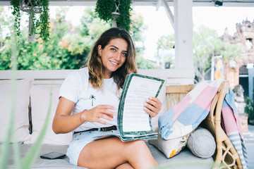Woman sitting on sofa with papers in hands and smiling outdoor