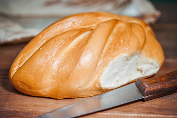 loaf of white bread lies on a wooden board.