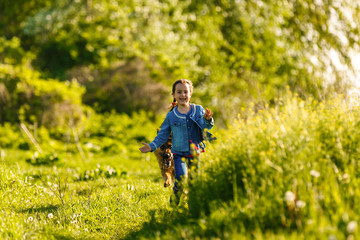 Portrait of a beautiful happy little girl with a puppy German shepherd outdoors