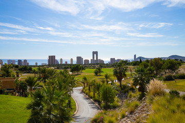 Green golf course and skyscrapers on the horizon and blue sky with beautiful clouds in Benidorm, Spain