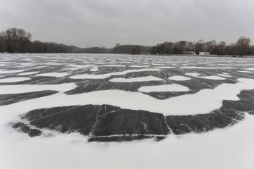 Blizzard and snow storm in the city on a frozen pond. Residential buildings on the banks of the...