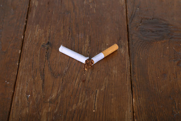 Broken filter cigarette lies on a wooden table