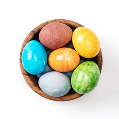 Different easter eggs in wooden bowl isolated on white