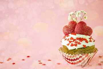 St. Valentine's Day card. Cupcake with white cream and red sugar hearts and a box with a gift on a pink background, bokeh effect, copy space