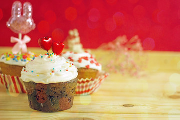 Valentines day cupcake. A cupcake with white cream is decorated with two red hearts on a red copy space background. Beautiful St. Valentine's Day card