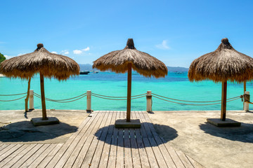 Straw umbrellas on the background of the Sulu Sea. Luxury beach resort in Boracay, The Philippines.