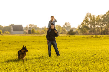 Father and toddler walking with dog