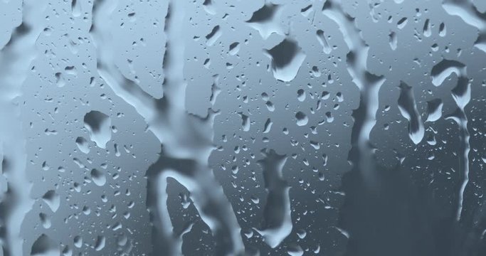 Strong rain water flushes against window glass and streaming down. Close up, zoom in. Weather concept background