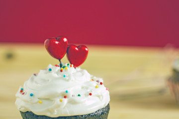 St valentines day background.  White cream on a cupcake decorated with two red hearts close-up of copy space. Beautiful St. Valentine's Day card