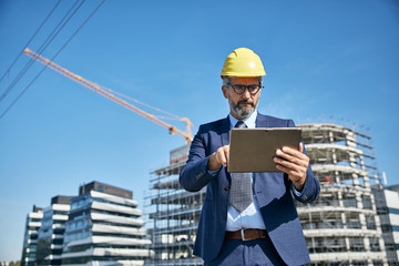 senior businessman architect helmet construction site building architecture tablet computer