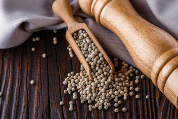 white peppercorns in wooden scoop on rustic background