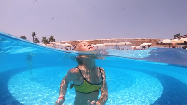 Happy girl playing in outdoor swimming pool on summer vacation on tropical beach.