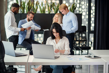 Young exuberant female office worker looking at camera with lovely smile at her workplace in meeting room