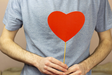 Valentine's day concept Valentine's day. Men's hands hold a red heart on a white wooden background....