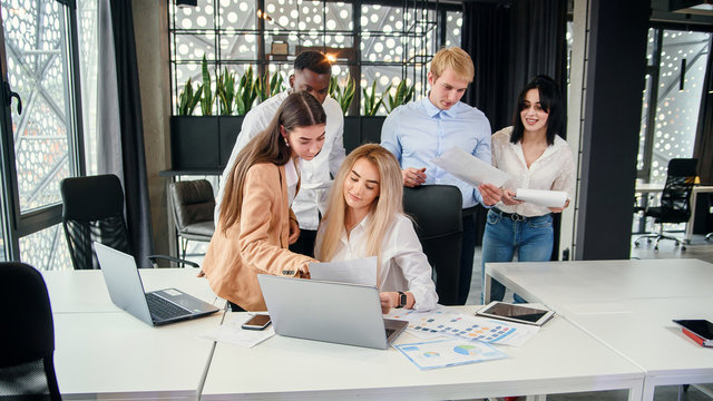 Successful young mixed race work team analysing financial report during their work under joint project at the boardroom table. Business and financial concept.