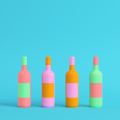 Four colorful wine bottles on bright blue background in pastel colors. Minimalism concept