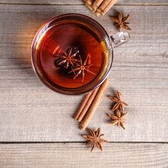 Spiced aromatic black tea. Hot warming beverage in a glass cup with anise and cinnamon on wooden background