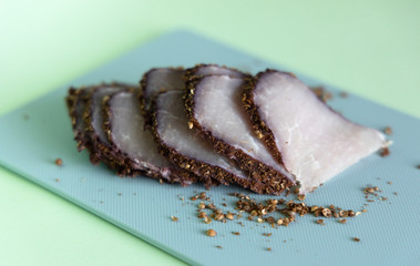 Sliced boiled pork on a blue cutting board on a mint background. An ingredient for a ketogenic diet. Low carbohydrate, high fat.