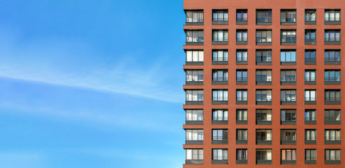 The modern brick facade of a high-rise building against the blue sky