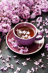 Tea cup and lilac on  dark table