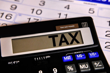 Tax text on black calculator on calendar